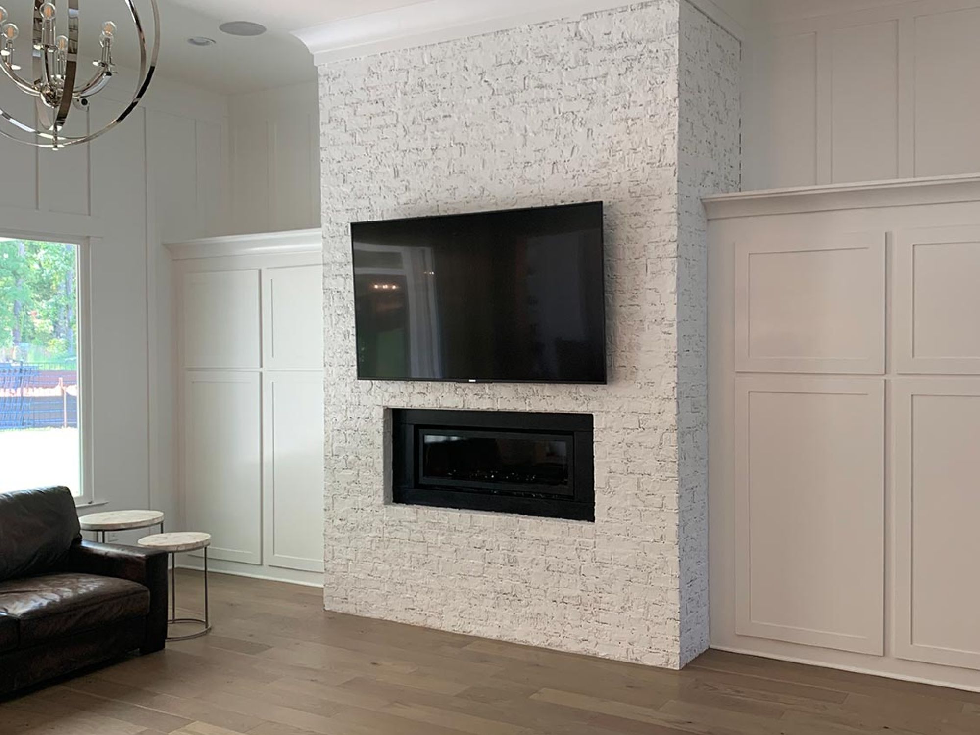 TV above a white brick fireplace wall